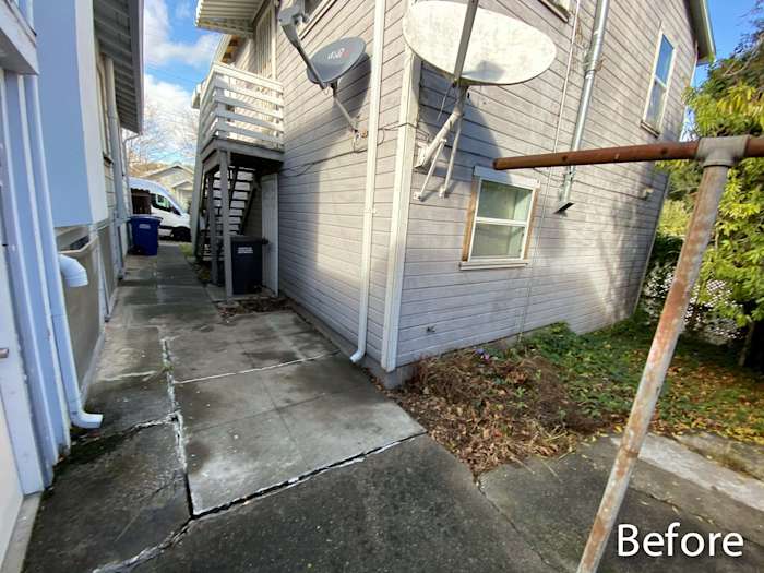 Before view of the side yard showing old siding, concrete pathway, and stairs leading to the deck in Rio Vista