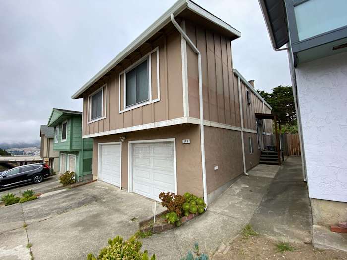 Daly City home featuring newly installed James Hardie siding in warm beige tones and updated garage doors