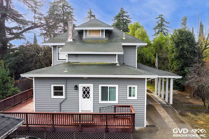 New light gray vinyl siding on a two-story home, featuring a multi-pitched roof and wraparound deck