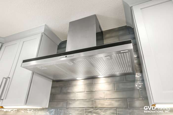 Modern stainless steel range hood above gray subway tile backsplash in remodeled Rocklin kitchen