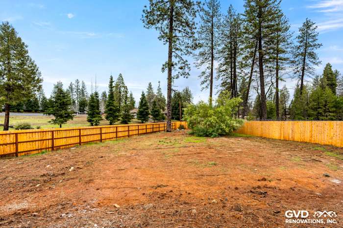 Cleared lot with wooden fence, surrounded by trees in Paradise, CA, ready for new construction