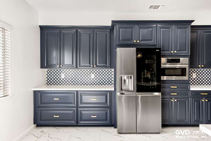 Navy blue kitchen cabinets, stainless steel appliances, and mosaic tile backsplash in Sacramento remodel