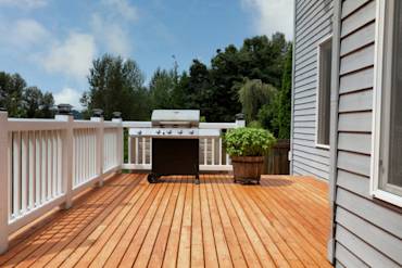 Spacious wooden deck with grill, surrounded by white railings and potted plant, showcasing outdoor living in Sacramento