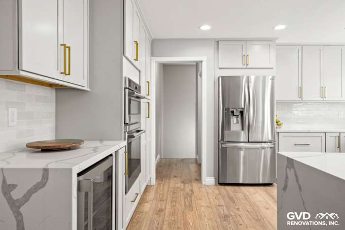 Modern kitchen with quartz countertops, custom cabinets, stainless steel appliances, and warm wood flooring