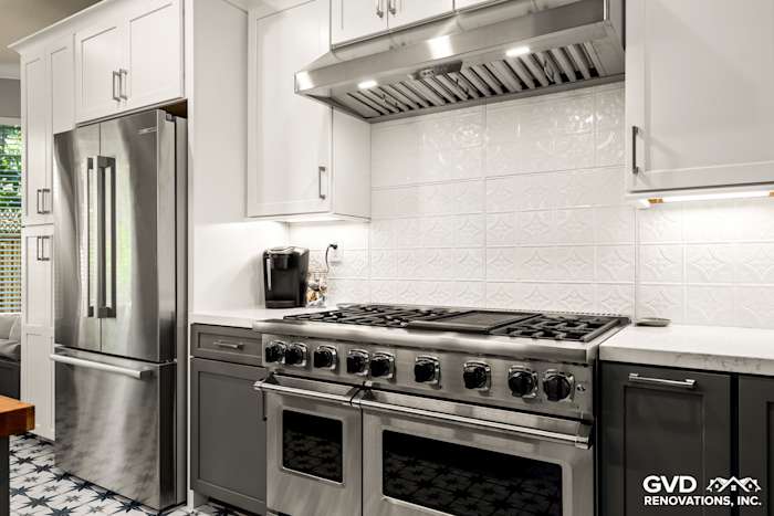 Modern Folsom kitchen featuring stainless steel appliances, intricate white backsplash, and sleek gray cabinetry