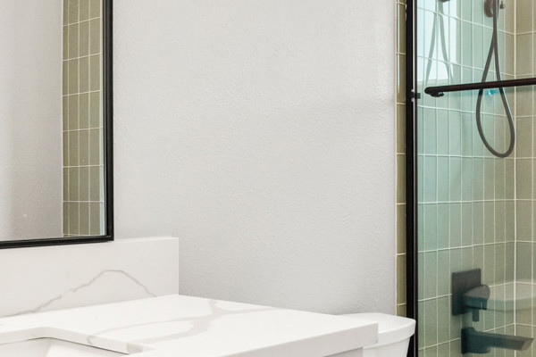 Modern guest bathroom with a glass shower, freestanding tub, and sleek vanity, featuring neutral tones and a stylish mirror