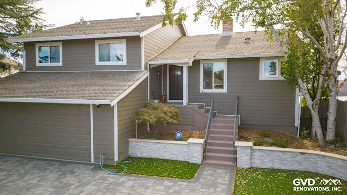 Home exterior featuring Timber Bark HardiePlank siding and Arctic White HardieTrim, complemented by a stone wall