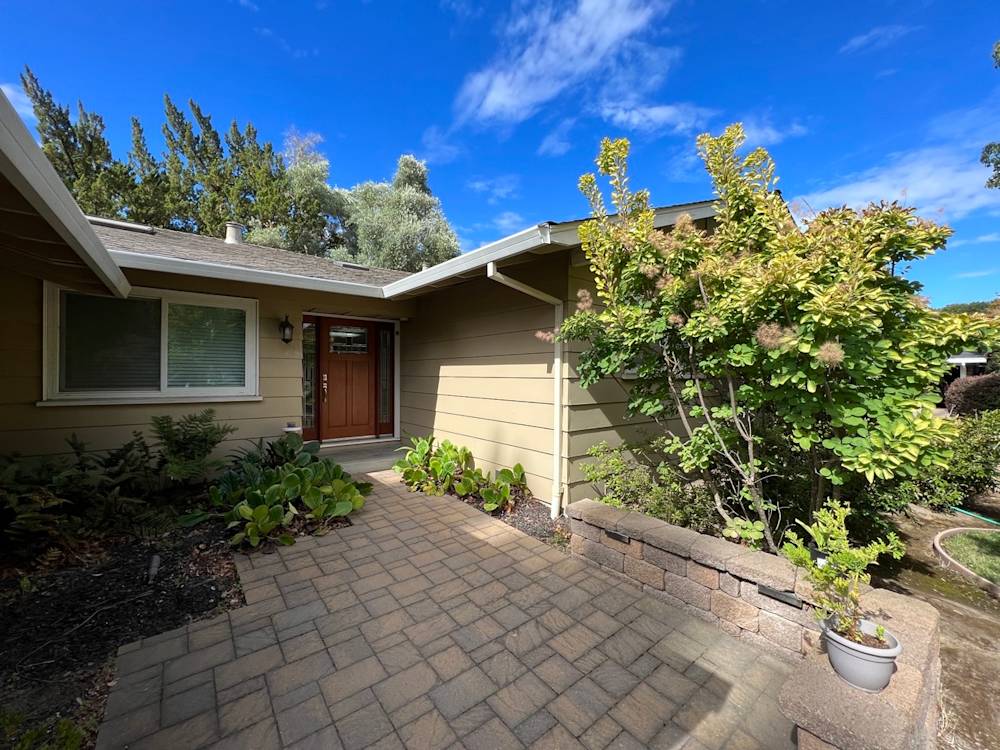 Welcoming entrance with paver stones, green landscaping, and a wooden door in Sacramento
