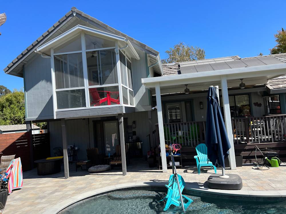 Split-level home exterior with gray siding and large glass windows in Sacramento