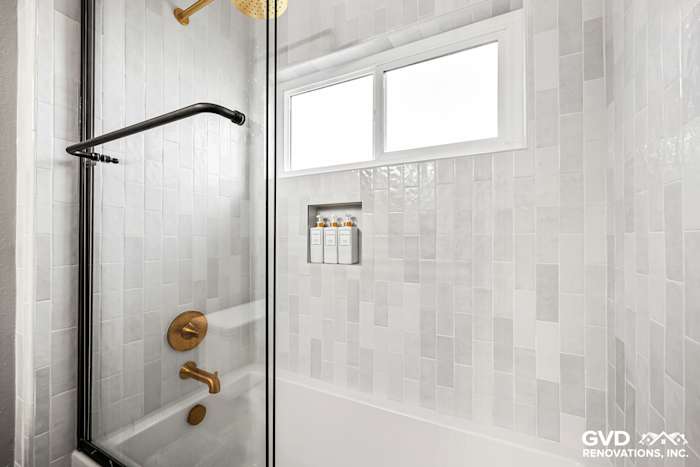 Modern guest bathroom shower with sliding glass door, marbled tile, and gold fixtures in El Dorado Hills