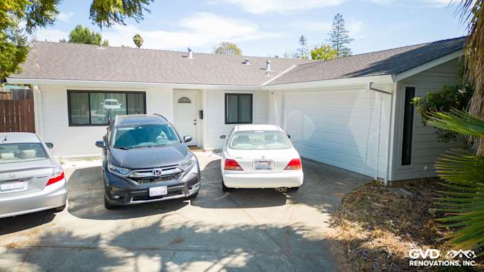 Renovated home exterior featuring James Hardie siding in Arctic White with driveway and parked cars