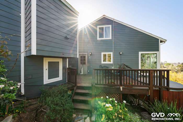Deep blue James Hardie lap siding with updated windows and wood deck in Oakland home exterior