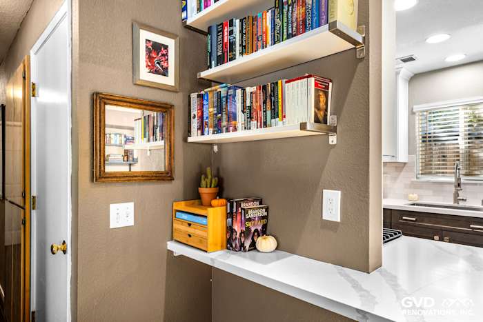 Modern kitchen nook featuring floating shelves with books, quartz countertop, and warm wall colors in Davis, CA