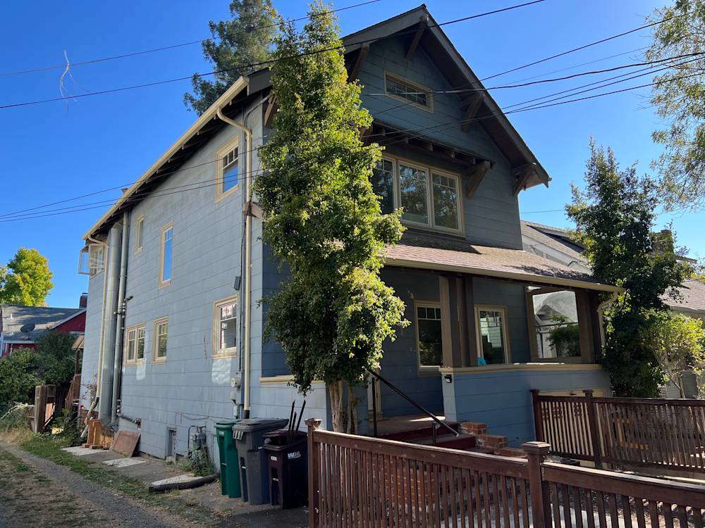 Old blue exterior with wooden accents, deck, and landscaped yard in Sacramento