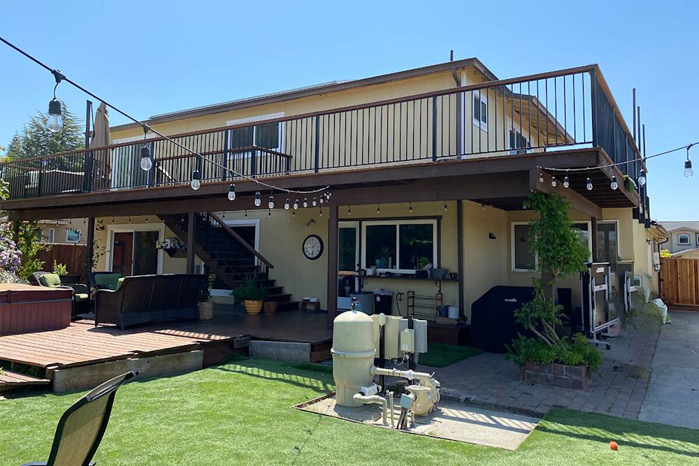 Worn exterior siding, beige color, outdated patio furniture, and old deck railings