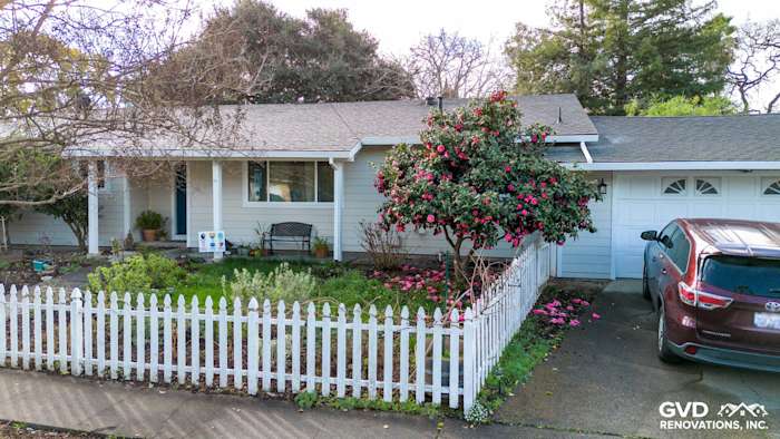 Napa home exterior featuring James Hardie Cobble Stone siding, Arctic White trim, and a floral garden with a white picket
