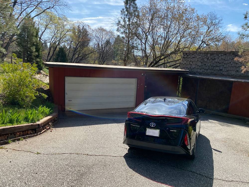 Red garage with wooden accents and a concrete driveway in Sacramento, surrounded by lush greenery
