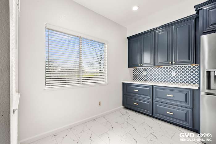 Modern kitchen with navy blue cabinets, white subway tile backsplash, and marble flooring in Sacramento remodel