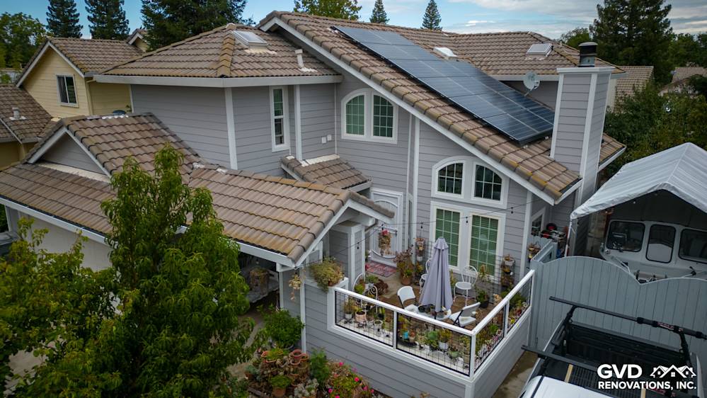 Home exterior featuring James Hardie Pearl Gray siding and Arctic White trim with solar panels, garden patio visible