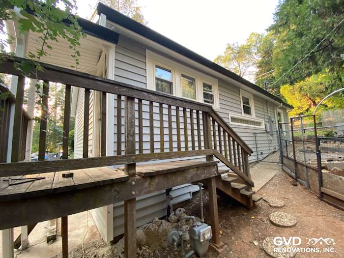 Newly installed Prodigy vinyl siding in light gray on a home's side with a wooden deck and staircase in Grass Valley