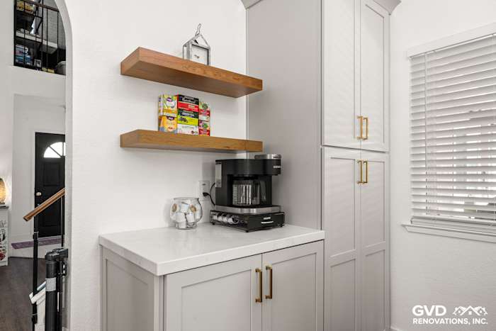 Modern kitchen corner with Waypoint cabinetry, Vadara Naurelle stone countertop, and floating wooden shelves in Roseville, CA
