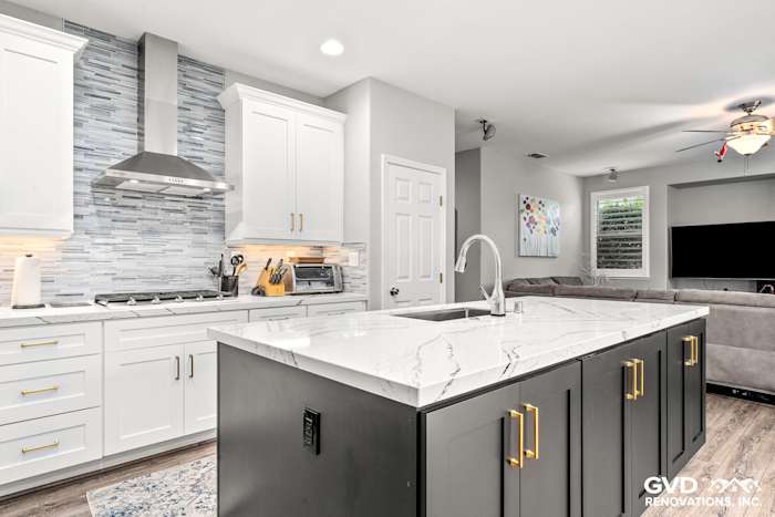 Modern kitchen with Cambria custom countertops, white cabinets, gray backsplash, and open layout