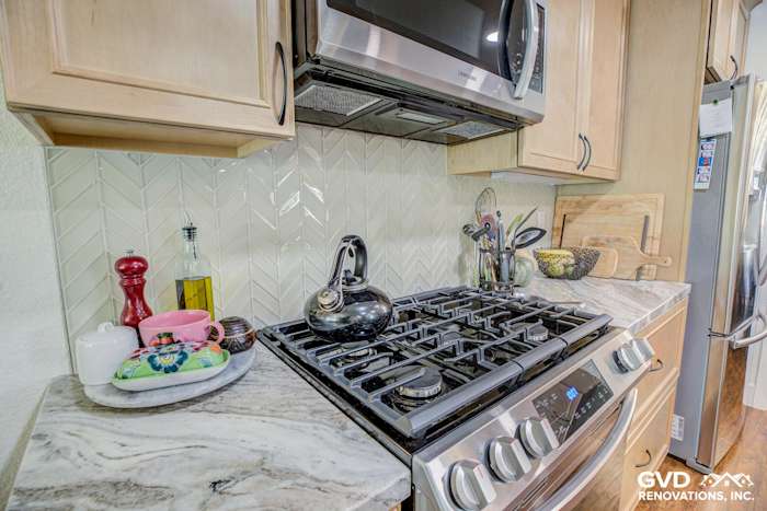 Modern kitchen countertop featuring herringbone backsplash, stainless steel appliances, and elegant marble surface
