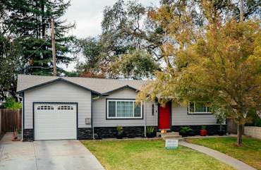 Modern home exterior with gray James Hardie siding, red door, and stone accents in Sacramento