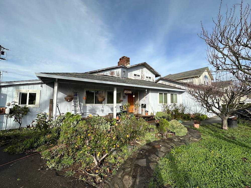 Exterior view of a quaint Northern California home with a stone walkway and lush greenery