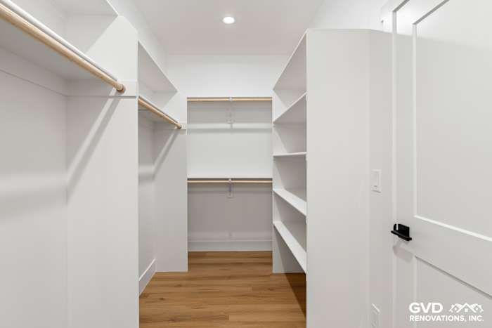 Spacious walk-in closet featuring white shelving, wood accents, and ample storage in new construction home