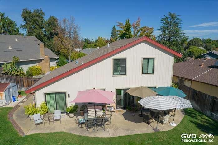 Updated home exterior featuring T1-11 siding, Anlin windows, and outdoor seating with umbrellas in Orangevale