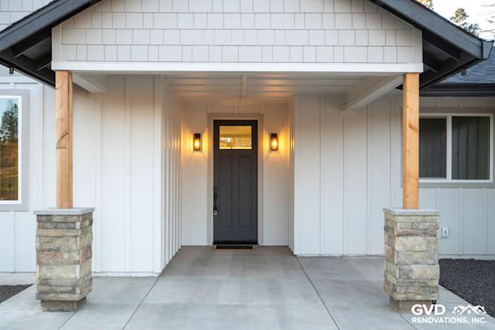 Modern entryway of a new construction home in Paradise, featuring James Hardie board and batten siding, stone pillars, and