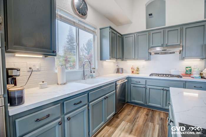 Modern kitchen with gray cabinetry, marble countertops, and bright white subway tile backsplash in El Dorado Hills