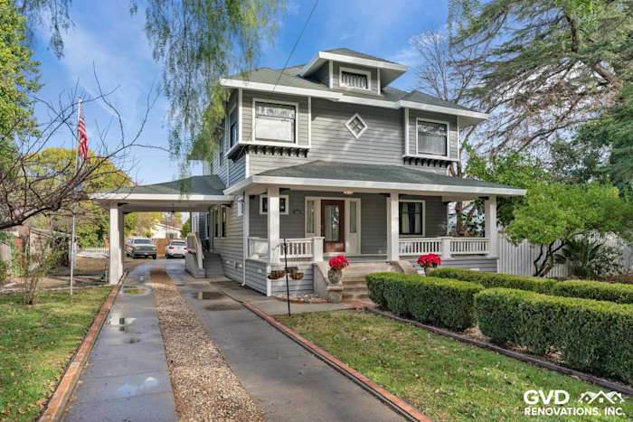 Two-story home in Dixon, CA, featuring new gray vinyl siding, a porch, and landscaped garden beds