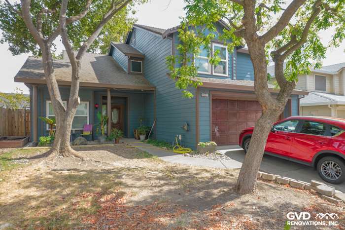Freshly renovated home exterior featuring primed and painted James Hardie siding in blue, Anlin windows, and red SUV