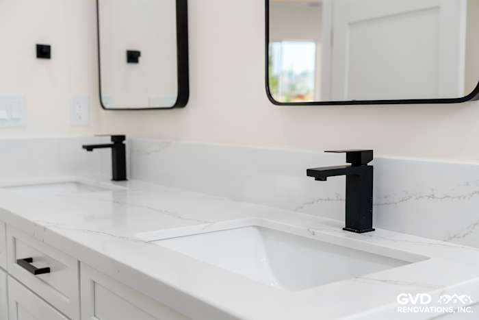 Modern bathroom vanity featuring black faucets, white countertop, and dual mirrors in Paradise, CA