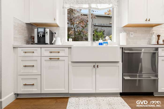 Modern kitchen featuring white Waypoint cabinets, a stainless steel sink, and a view of outdoor foliage
