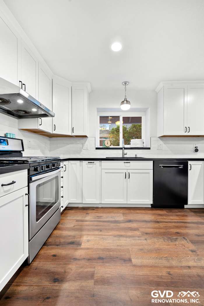 Modern white shaker kitchen with black accents, quartz countertops, and wood flooring in Loomis