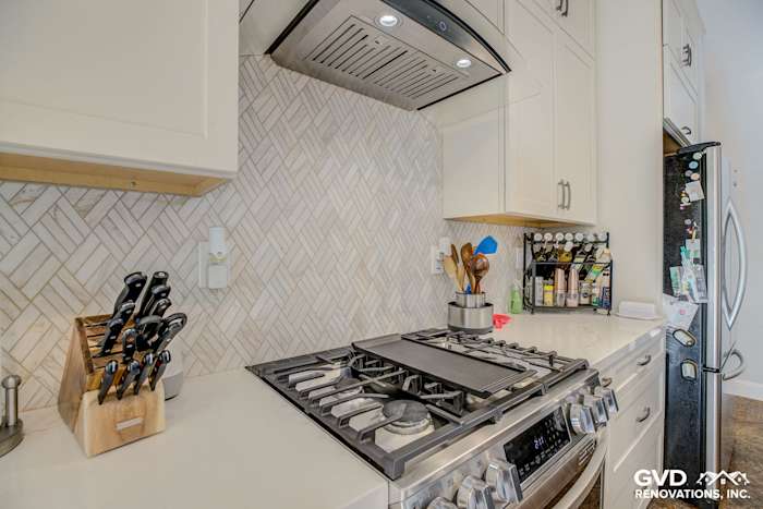 Modern kitchen with herringbone backsplash, stainless steel range, and organized knife block in Roseville remodel