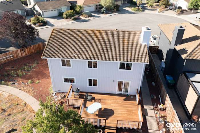 Upper view of a Petaluma home featuring new light gray siding, updated windows, and a spacious wood deck