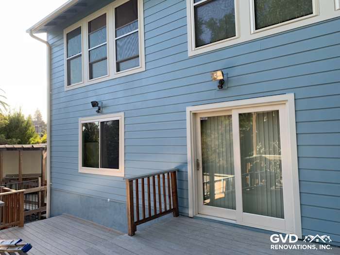 Blue James Hardie fiber cement siding with new vinyl windows and a wooden deck in Oakland, CA