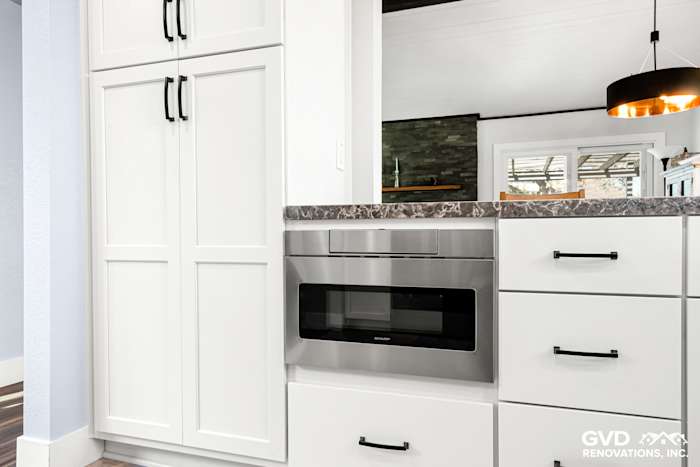 Modern kitchen remodel in Fair Oaks featuring white cabinets, stainless steel microwave, and dark granite countertop