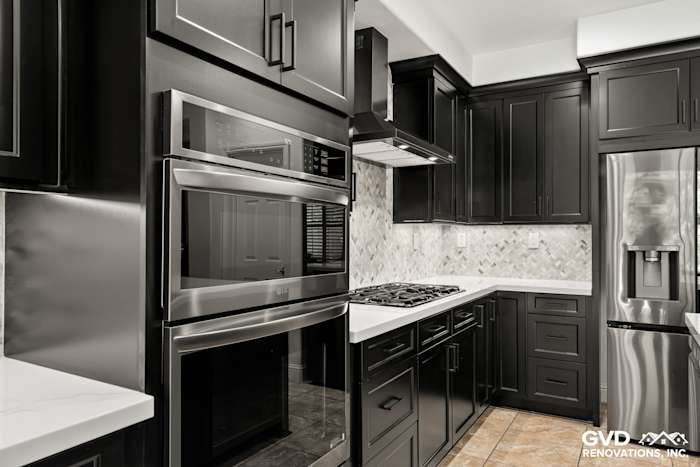 Modern kitchen with black Waypoint cabinets, MSI countertops, and a stylish mosaic backsplash in Roseville