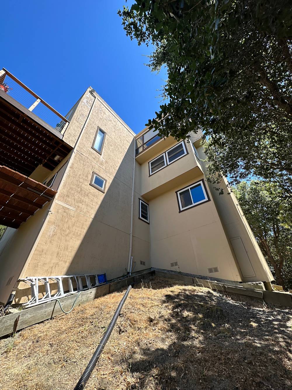 Old, beige exterior with worn surfaces and minimal landscaping