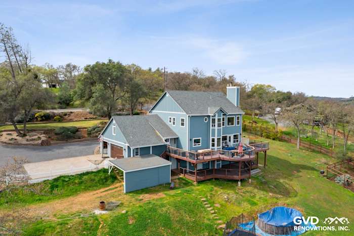 Newly installed James Hardie siding in blue on a spacious hillside home with a wraparound deck