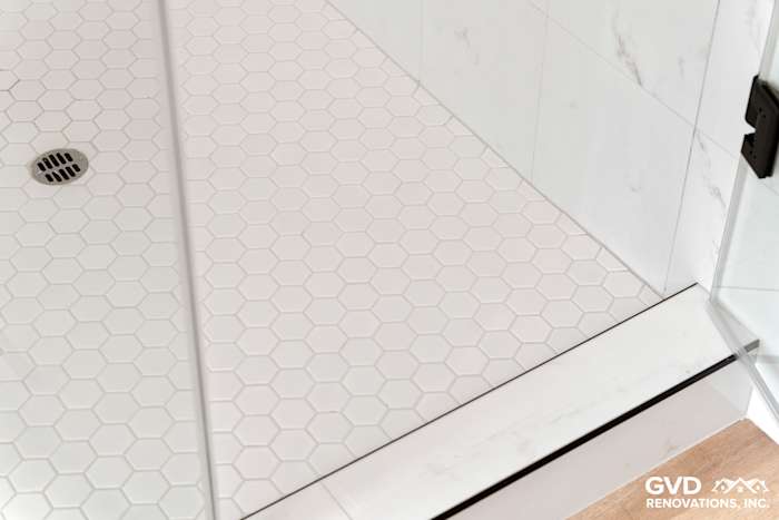 Hexagon white tile shower floor with a linear drain in a modern bathroom renovation
