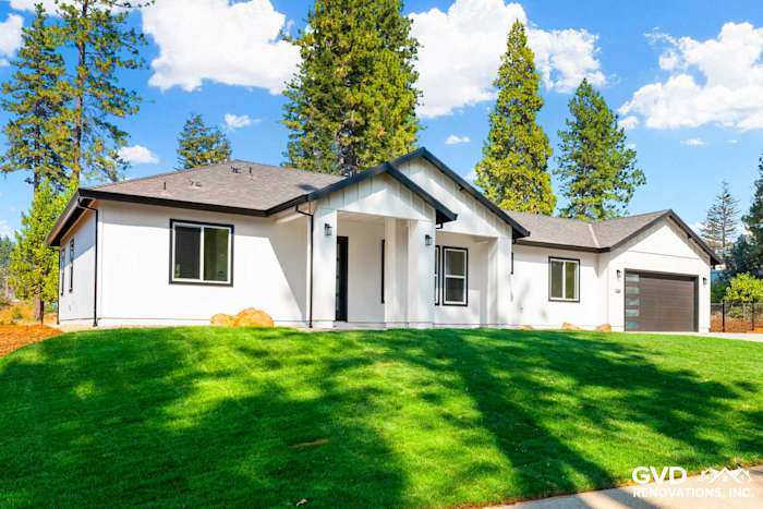 Modern single-story home exterior with white siding, black trim, and a landscaped green lawn in Paradise, CA
