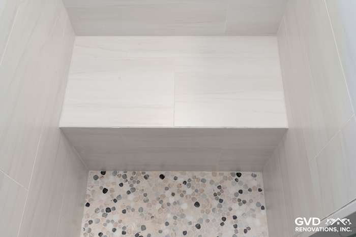 Modern shower niche with white wall tiles and a pebble floor in a Rocklin bath remodel
