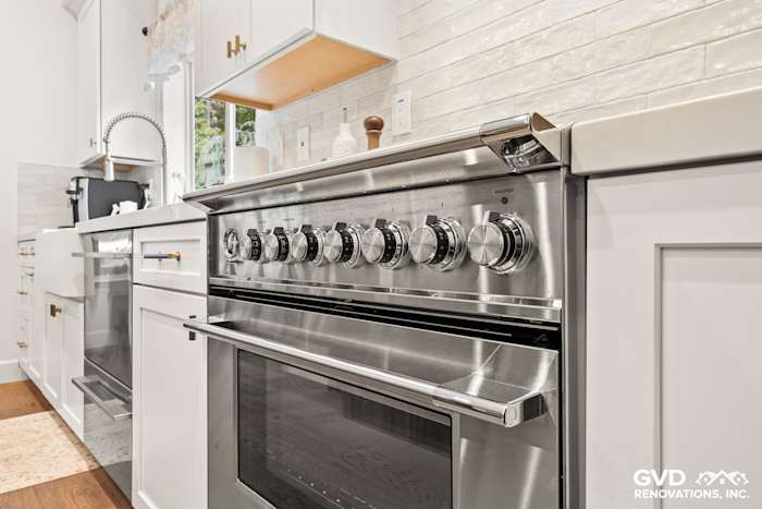 Modern kitchen with stainless steel range, white cabinetry, and textured tile backsplash in Folsom remodel