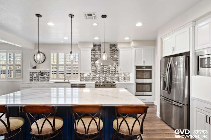 Modern kitchen remodel featuring a large white quartz island, stainless steel appliances, and patterned backsplash